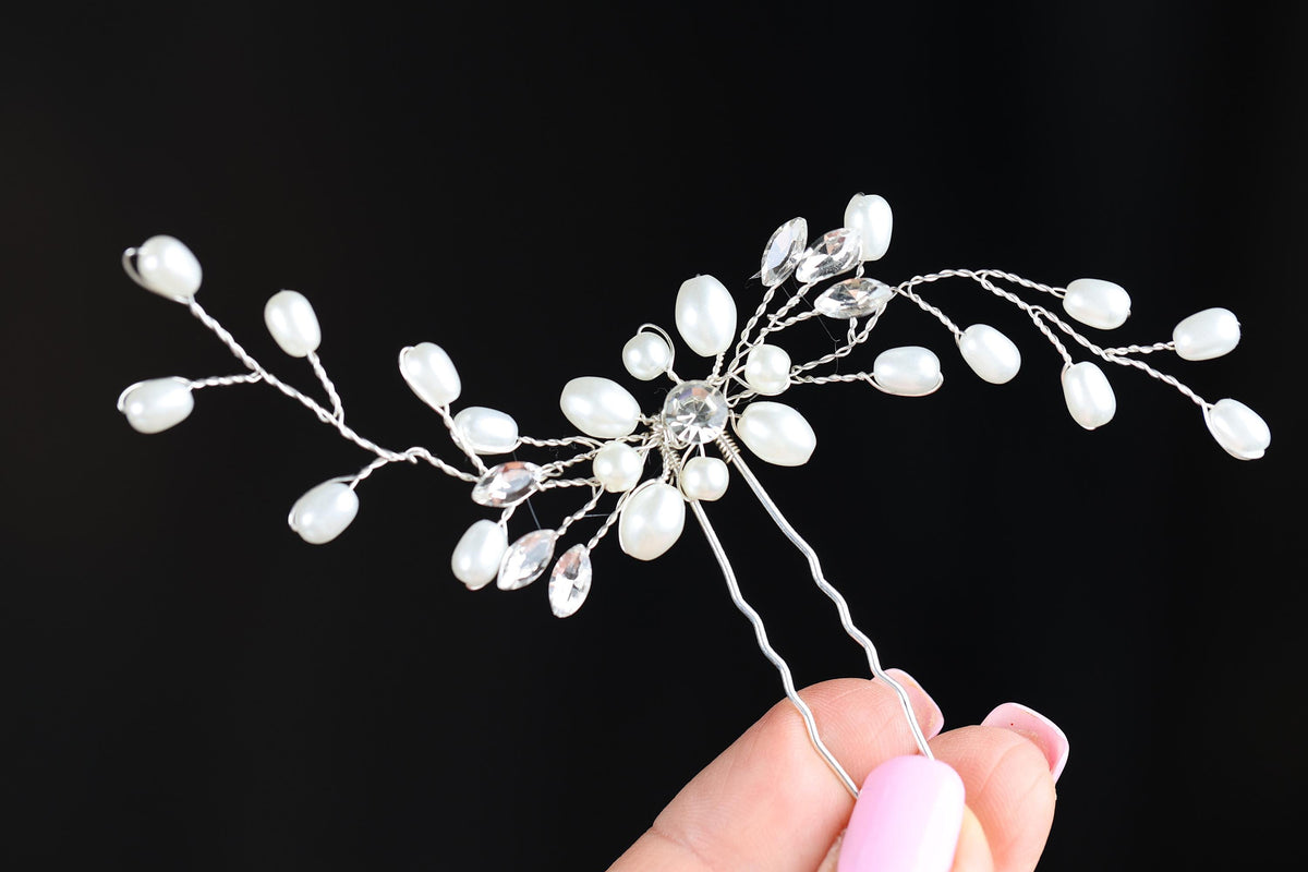 a hand holding a white flower head piece