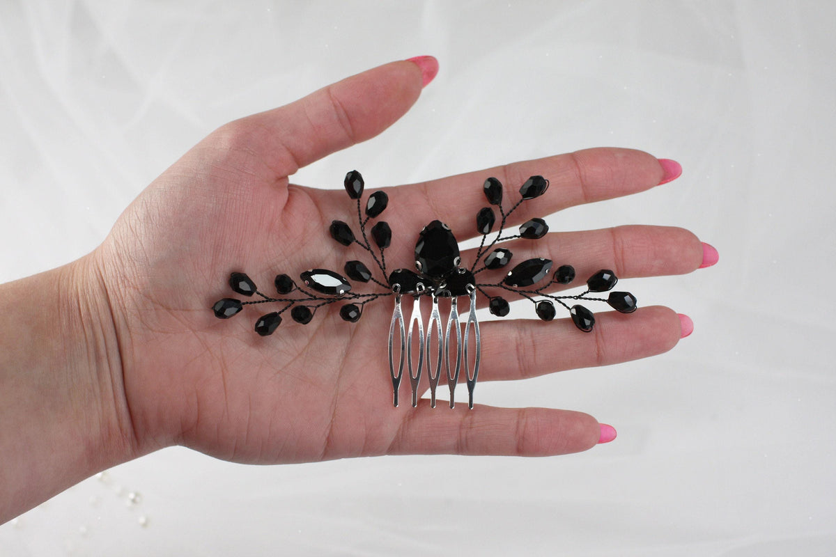 a woman's hand holding a comb with black beads on it