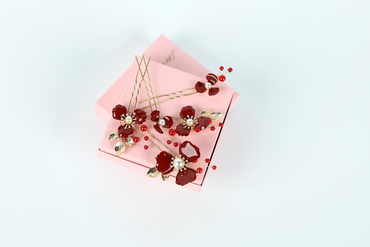 A pink box adorned with red and gold floral decorations, including red flowers and gold leaves, is placed on a white background.