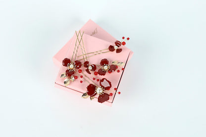 A pink box adorned with red and gold floral decorations, including red flowers and gold leaves, is placed on a white background.