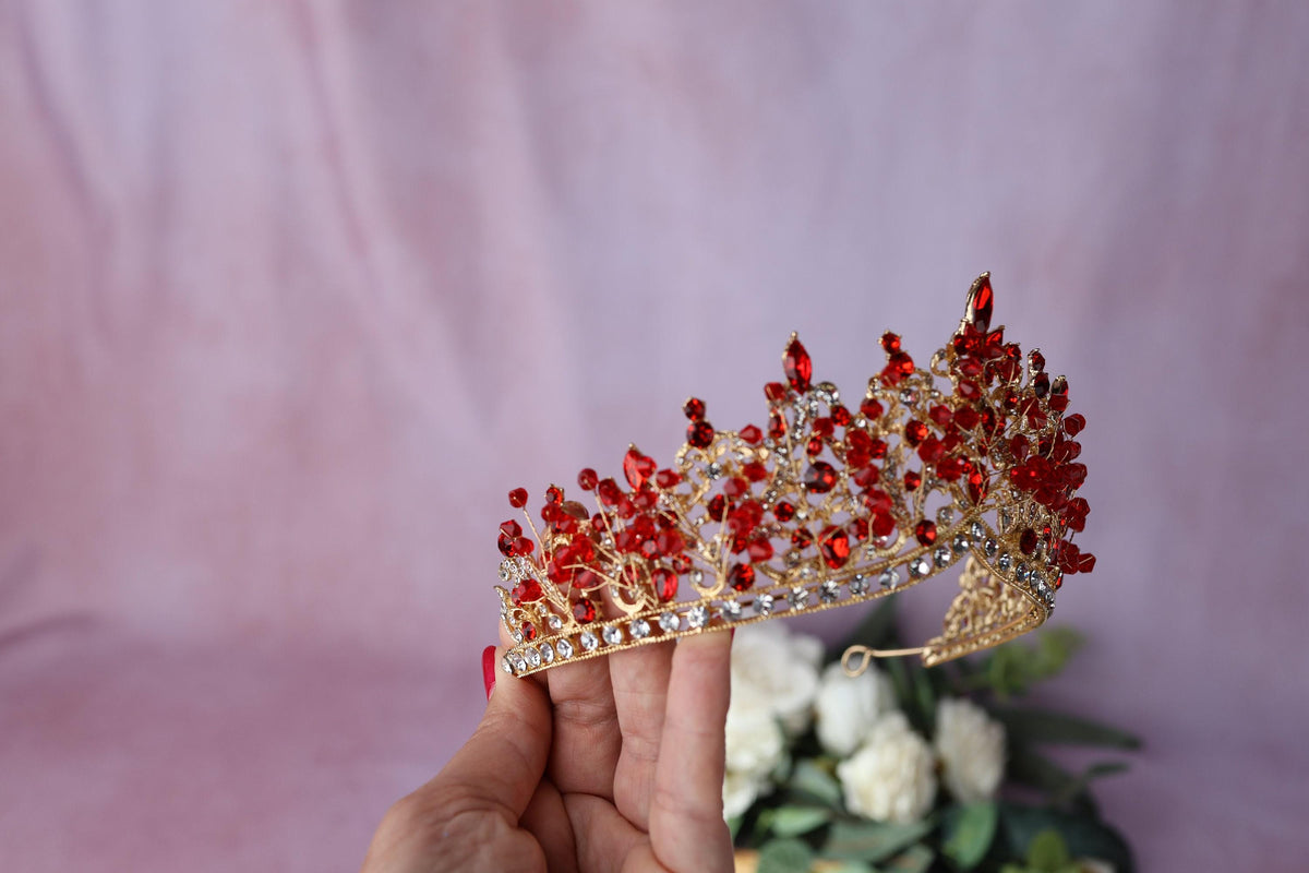 a hand holding a red and gold tiara