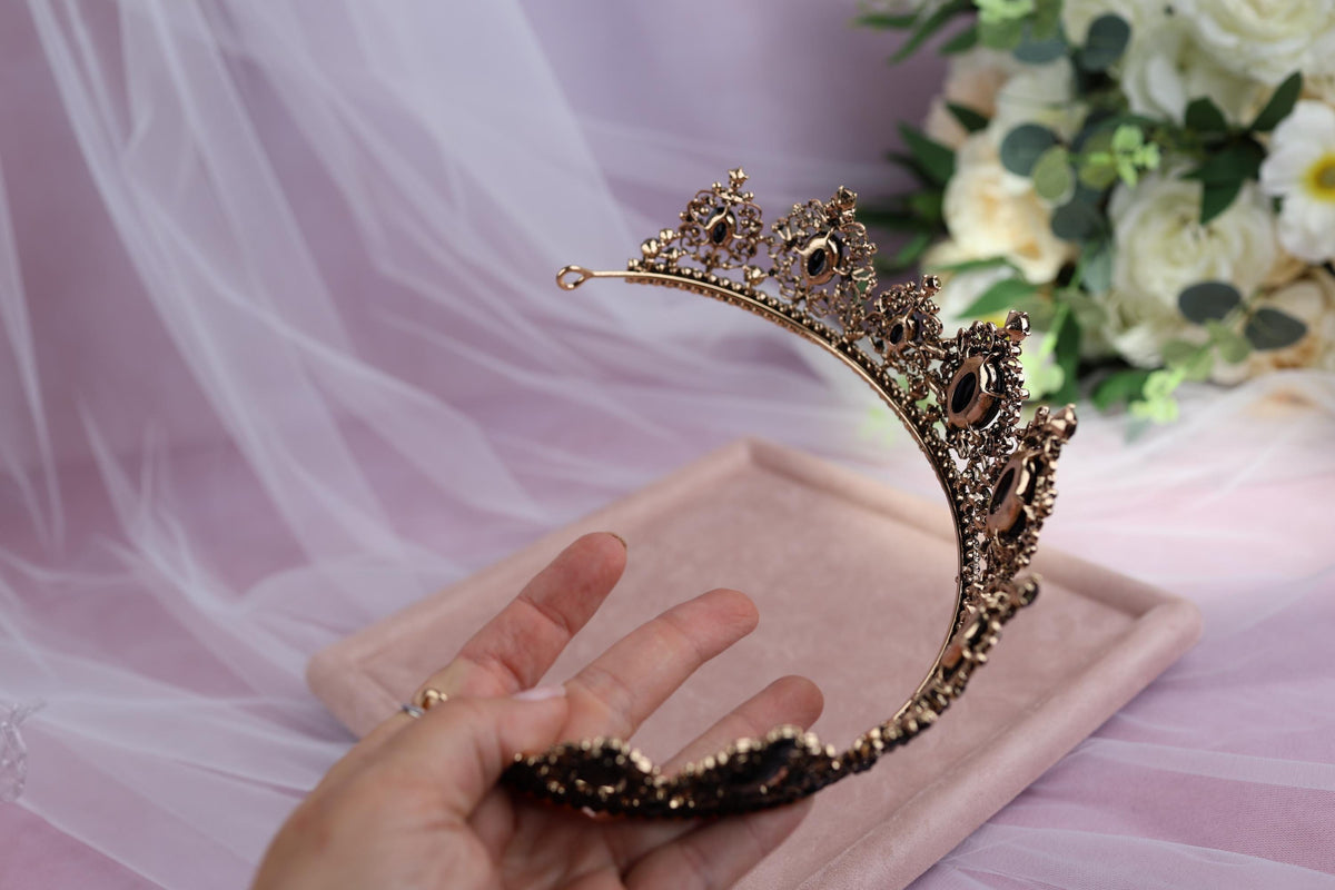 a hand is holding a tiara in front of a bouquet