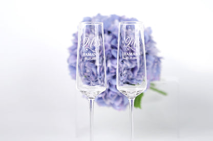 two champagne flutes with personalized messages, placed in front of a bouquet of purple flowers.