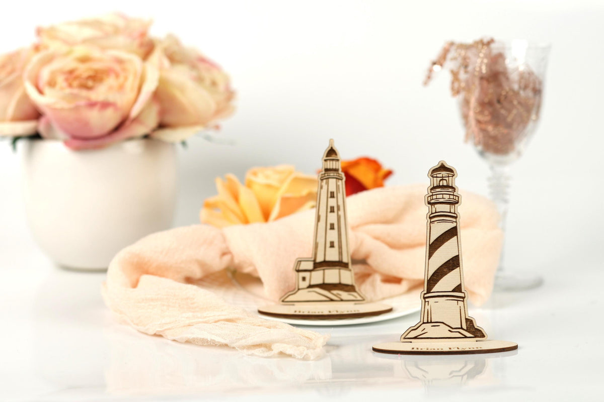 a white vase with pink roses, a wooden lighthouse, and a glass of wine, all set against a white background.