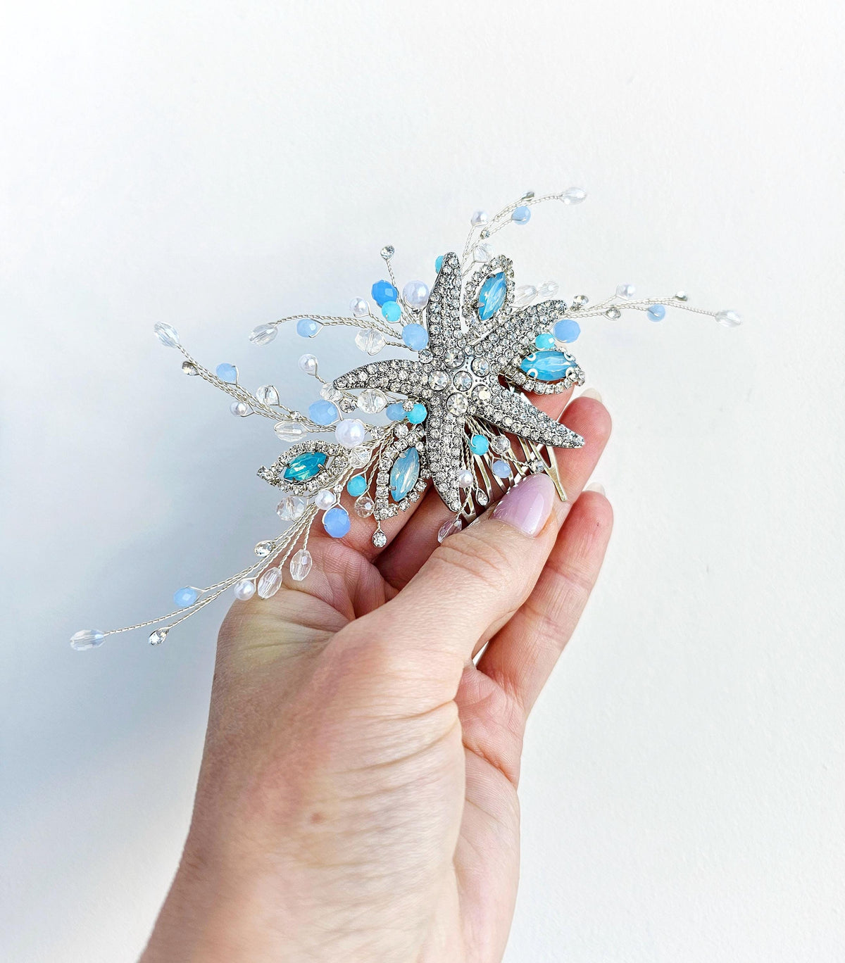 a hand holding a blue and white brooch