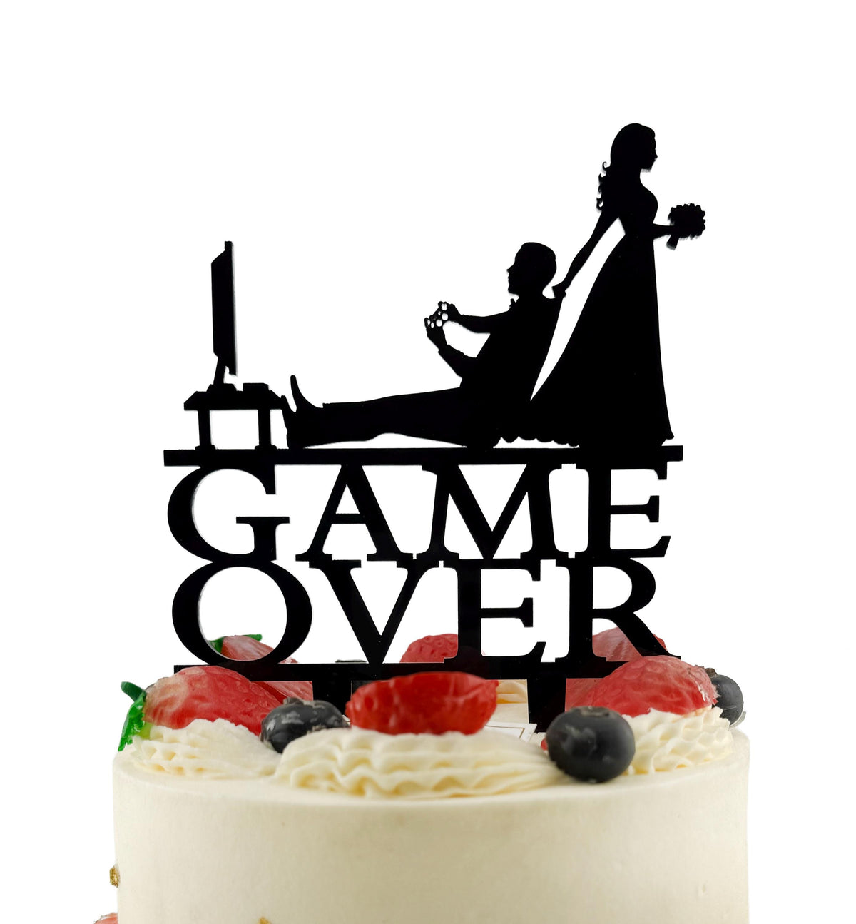 A silhouette of a bride and groom playing a video game on a cake topper with the text "GAME OVER" below it.