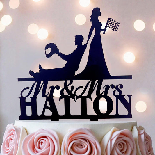 A silhouette of a man and a woman on a cake topper, with the text "Mr & Mrs HATTON" below them.