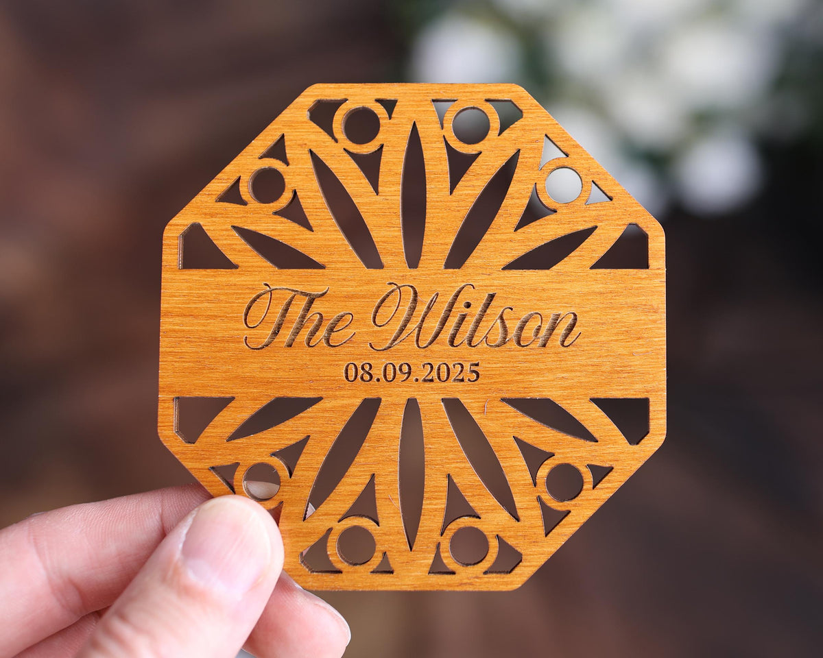 a person holding up a wooden coaster with the name of the wedding
