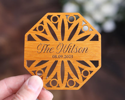 a person holding up a wooden coaster with the name of the wedding