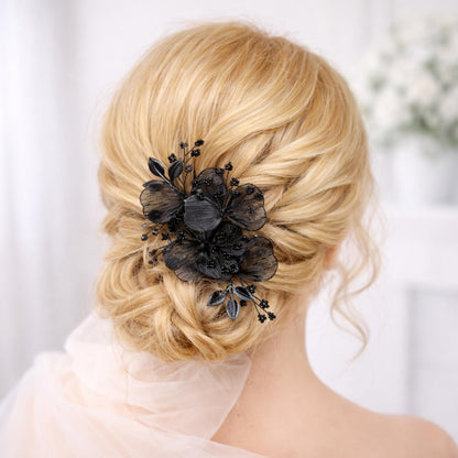 A close-up view of a woman's blonde hair with a black floral hair accessory, such as a flower or flower-shaped hair clip, in the back of her head.