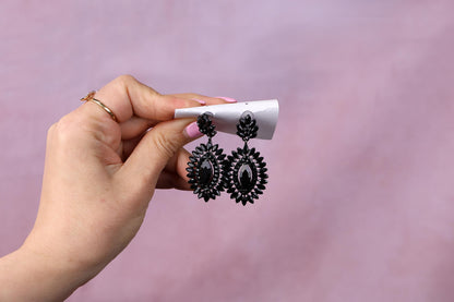 a woman holding a cigarette and a pair of earrings
