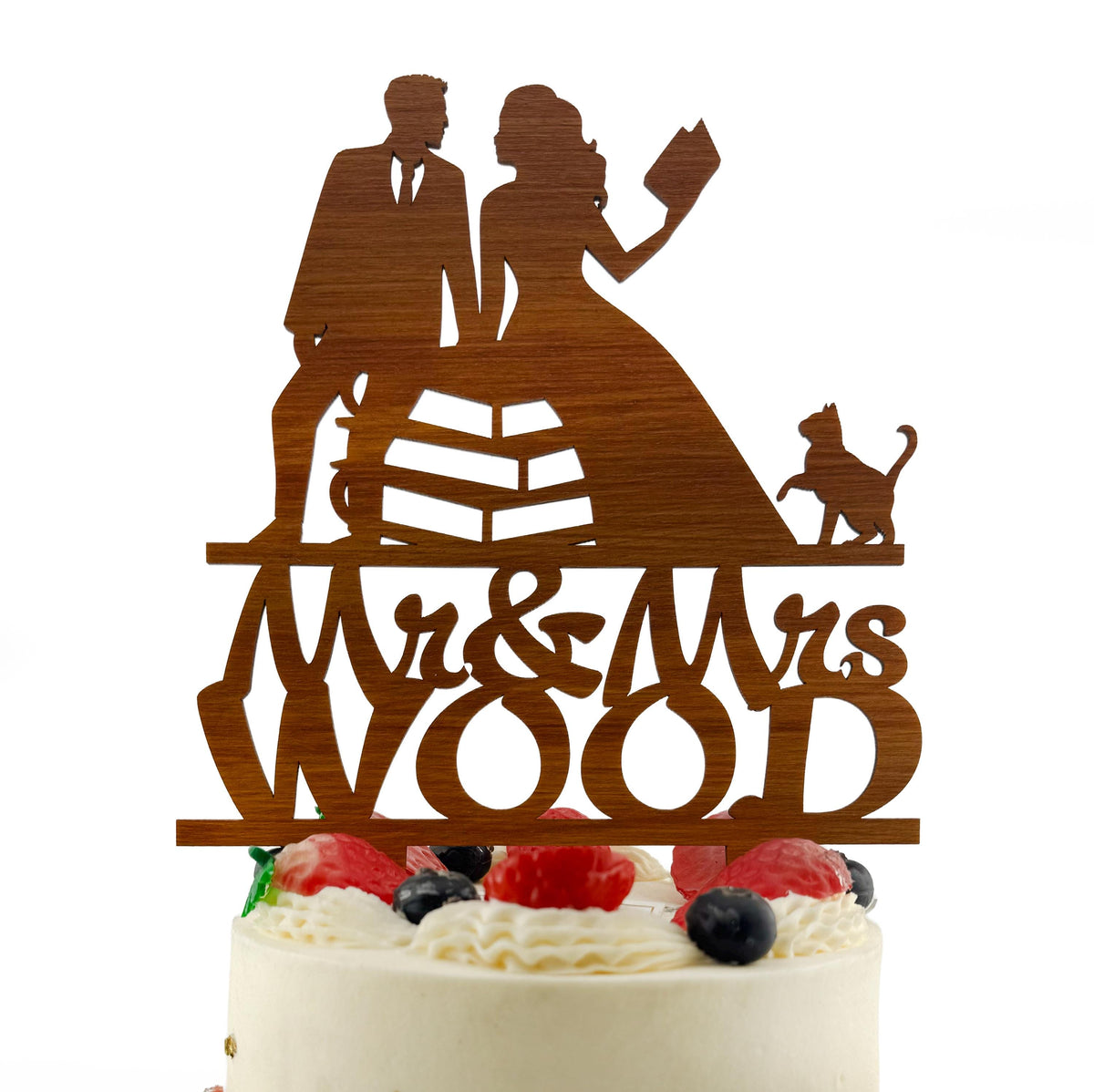 A wooden cake topper with the names 'Mr & Mrs Wood' written on it, featuring silhouettes of a man and a woman.
