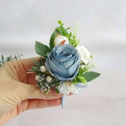 A hand holding a small, light blue rose with white flowers and greenery.
