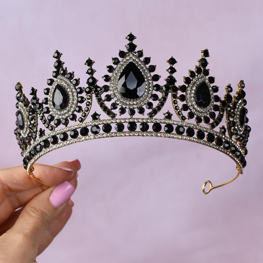 a woman holding a tiara with black stones on it