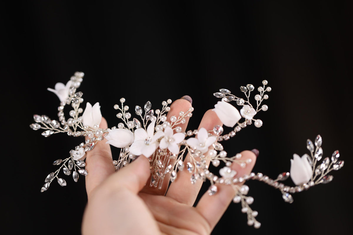 a hand holding a white flower and pearl hair comb