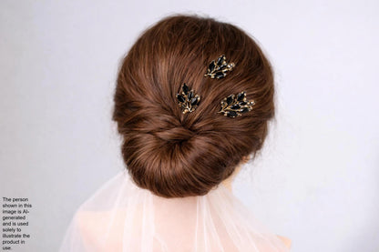 a woman's hair styled in a bun, with three decorative hair clips featuring black leaf-shaped designs attached to the hair.