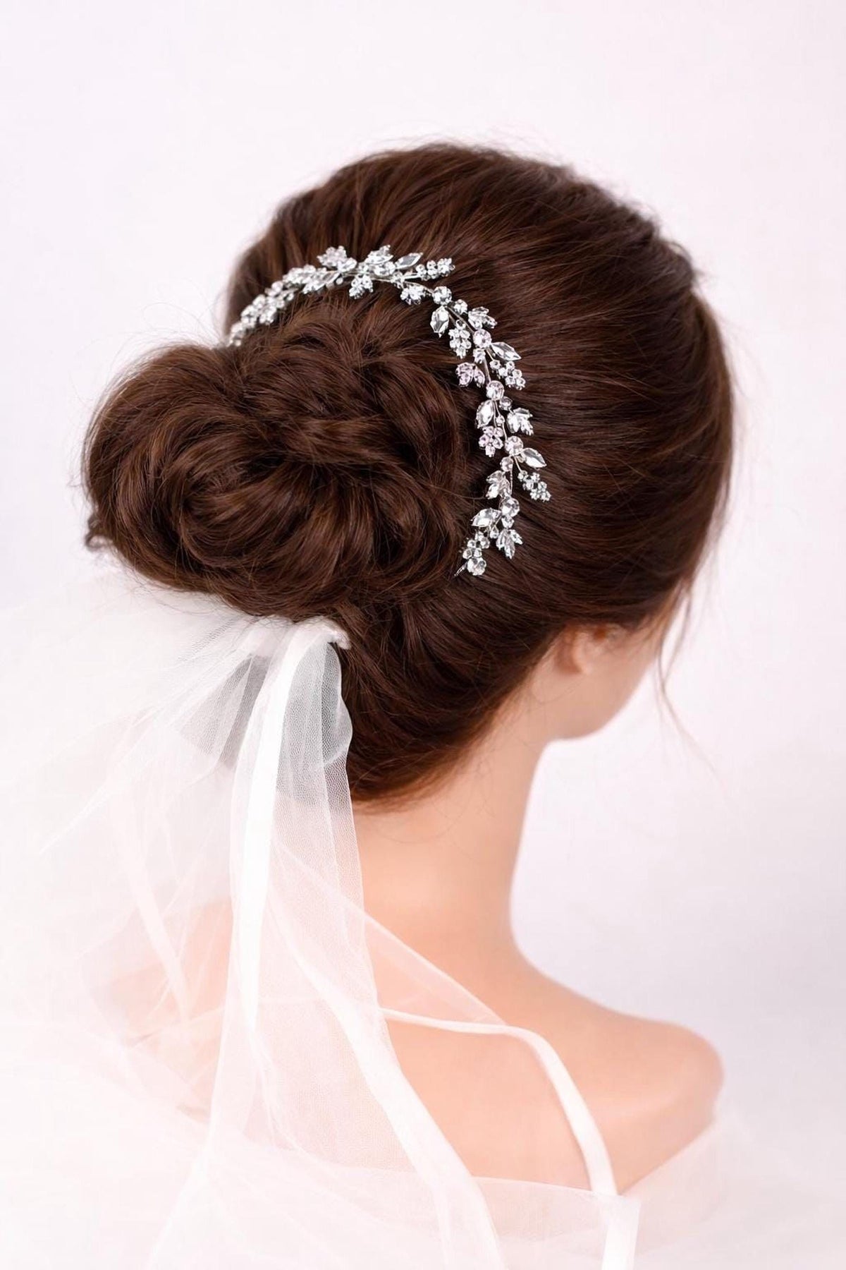 A woman's hair styled in a bun with a decorative hair accessory, likely a veil or headpiece, wrapped around it.
