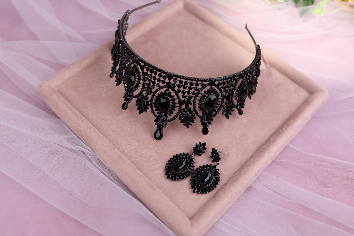 a black necklace and earrings on a pink plate