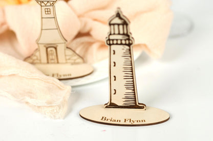 two wooden place cards with lighthouses on them, placed on a white surface.