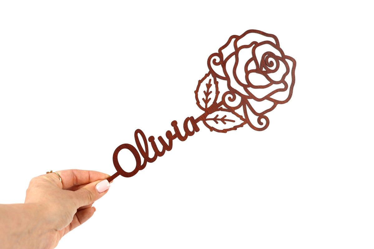 A hand holding a rose-shaped object with the name "Olivia" written on it.