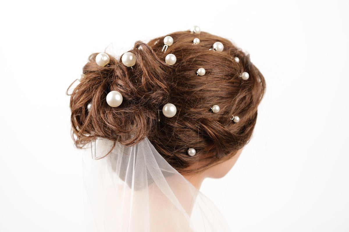 A close-up of a woman's hair adorned with numerous small white pearls, creating an elegant and intricate hairstyle.