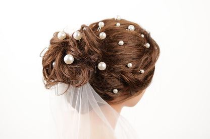 A close-up of a woman's hair adorned with numerous small white pearls, creating an elegant and intricate hairstyle.