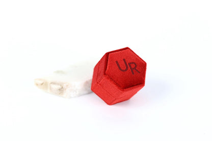 A red hexagonal object with the letters "UR" printed on it, placed on a white surface.