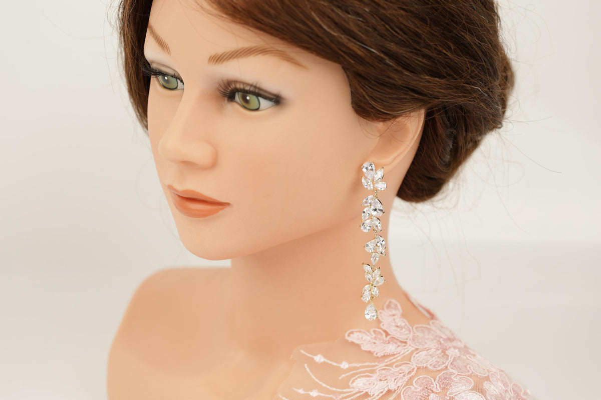 A close-up of a mannequin head wearing a pair of dangling earrings with a floral design.
