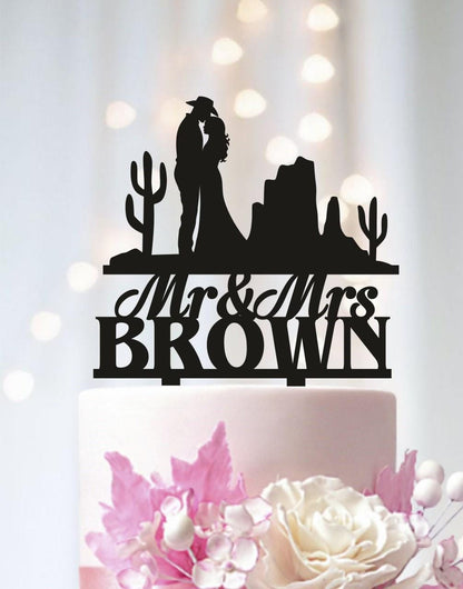 A black silhouette of a couple embracing, with the text "Mr & Mrs Brown" above them, on a wedding cake topper.