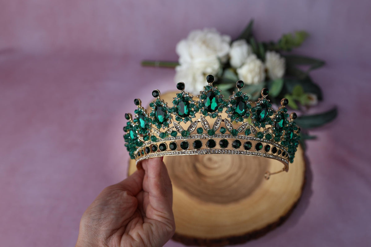 a hand holding a tiara next to a bouquet of flowers