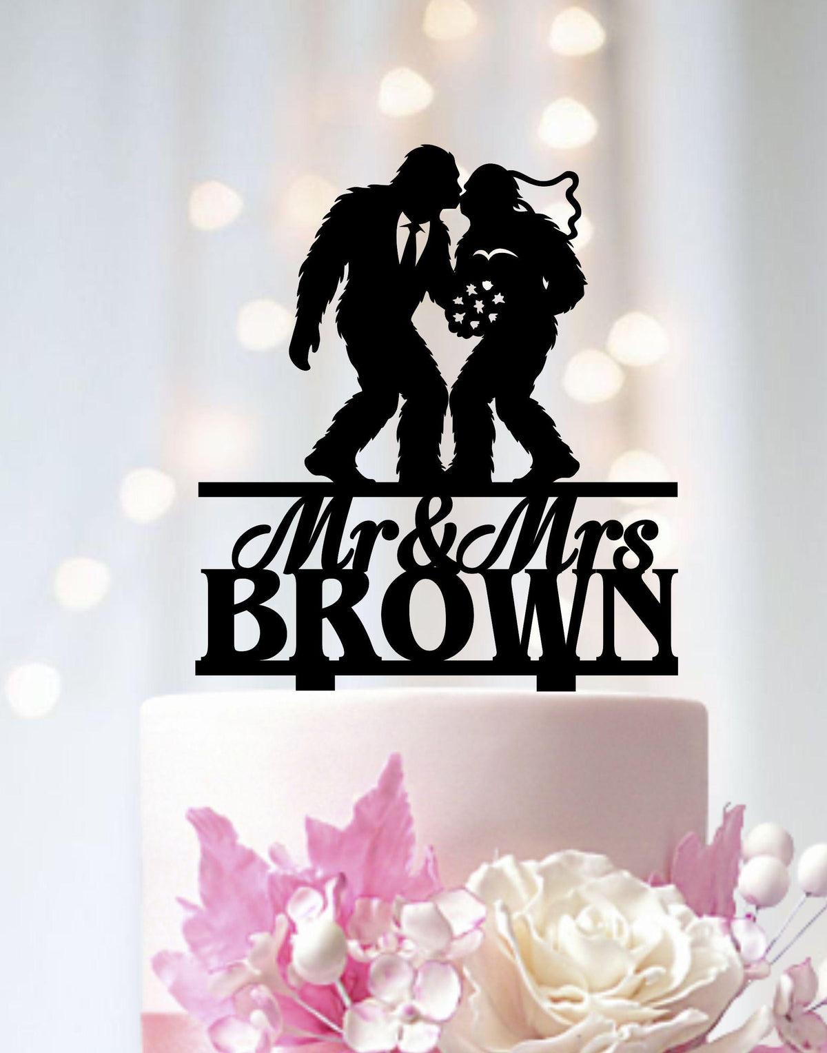 A black silhouette of a man and a woman kissing on top of a white wedding cake.