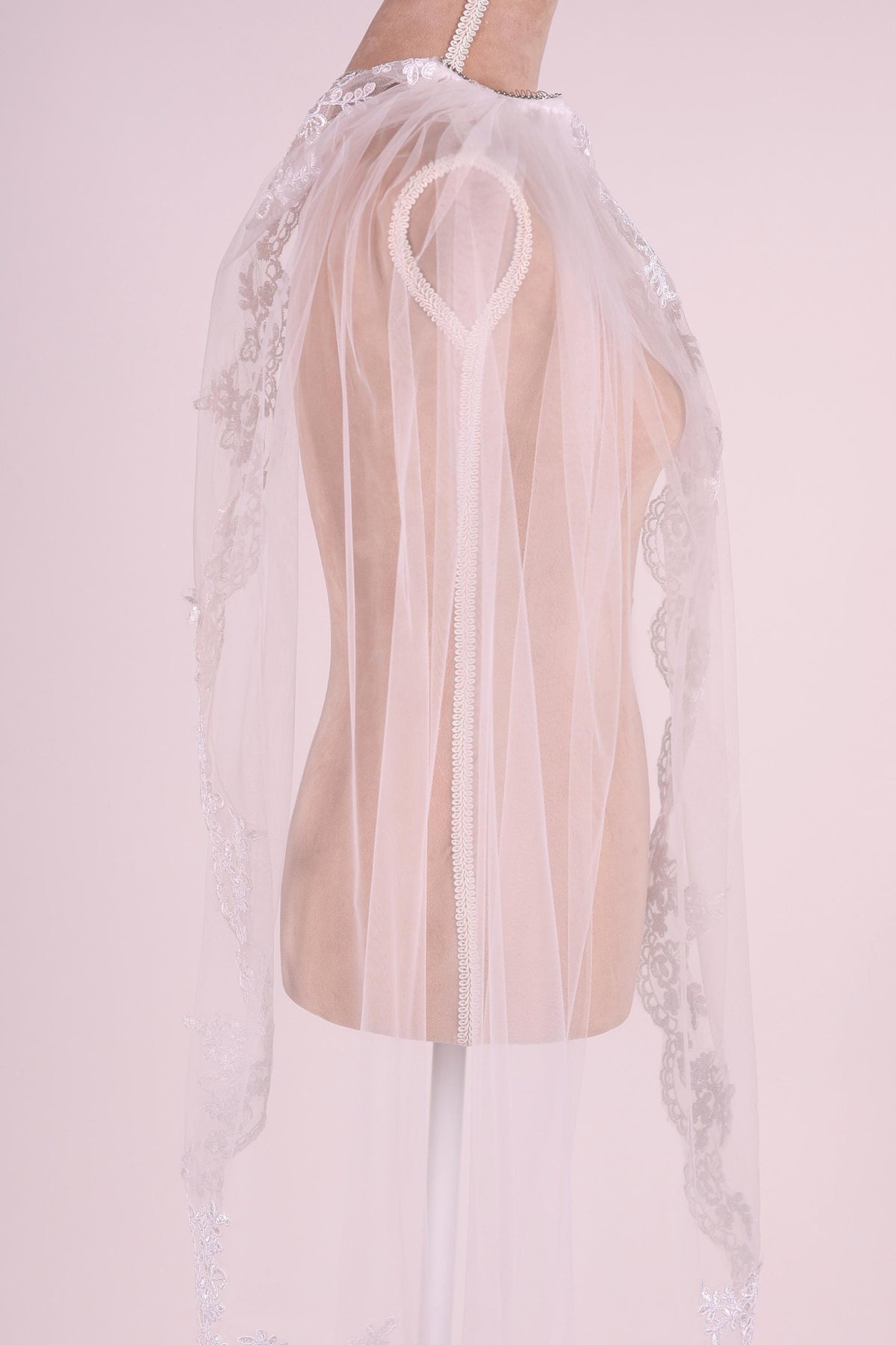 A mannequin wearing a white lace veil with a heart-shaped clasp.