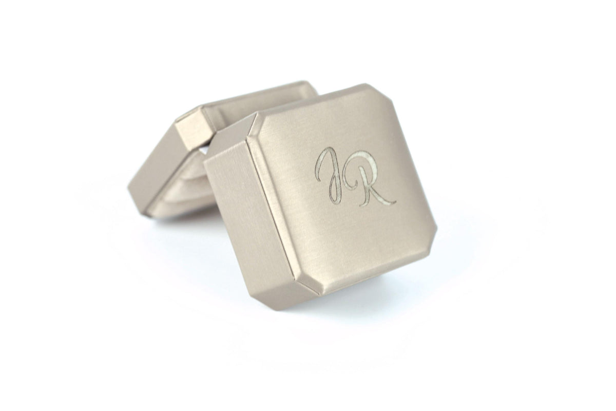 A silver-colored metal box with a personalized monogram engraved on it.