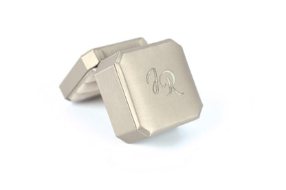 A silver-colored metal box with a personalized monogram engraved on it.