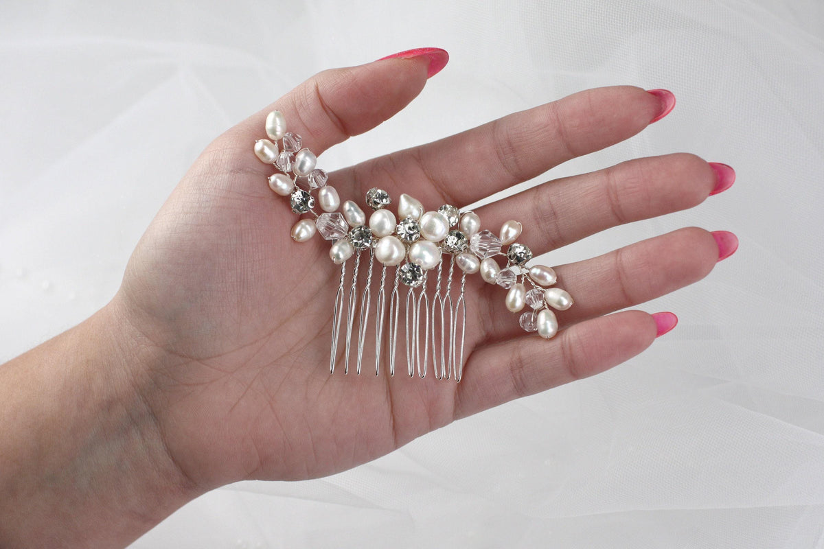 a woman's hand holding a hair comb with pearls on it