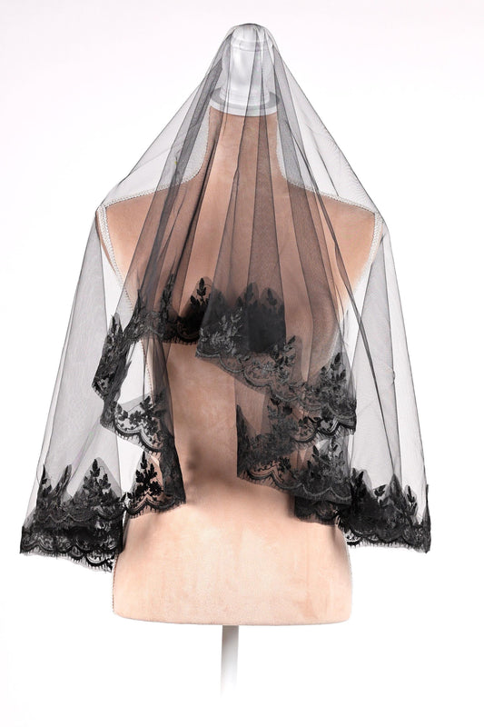 A mannequin wearing a black lace veil with intricate floral patterns.