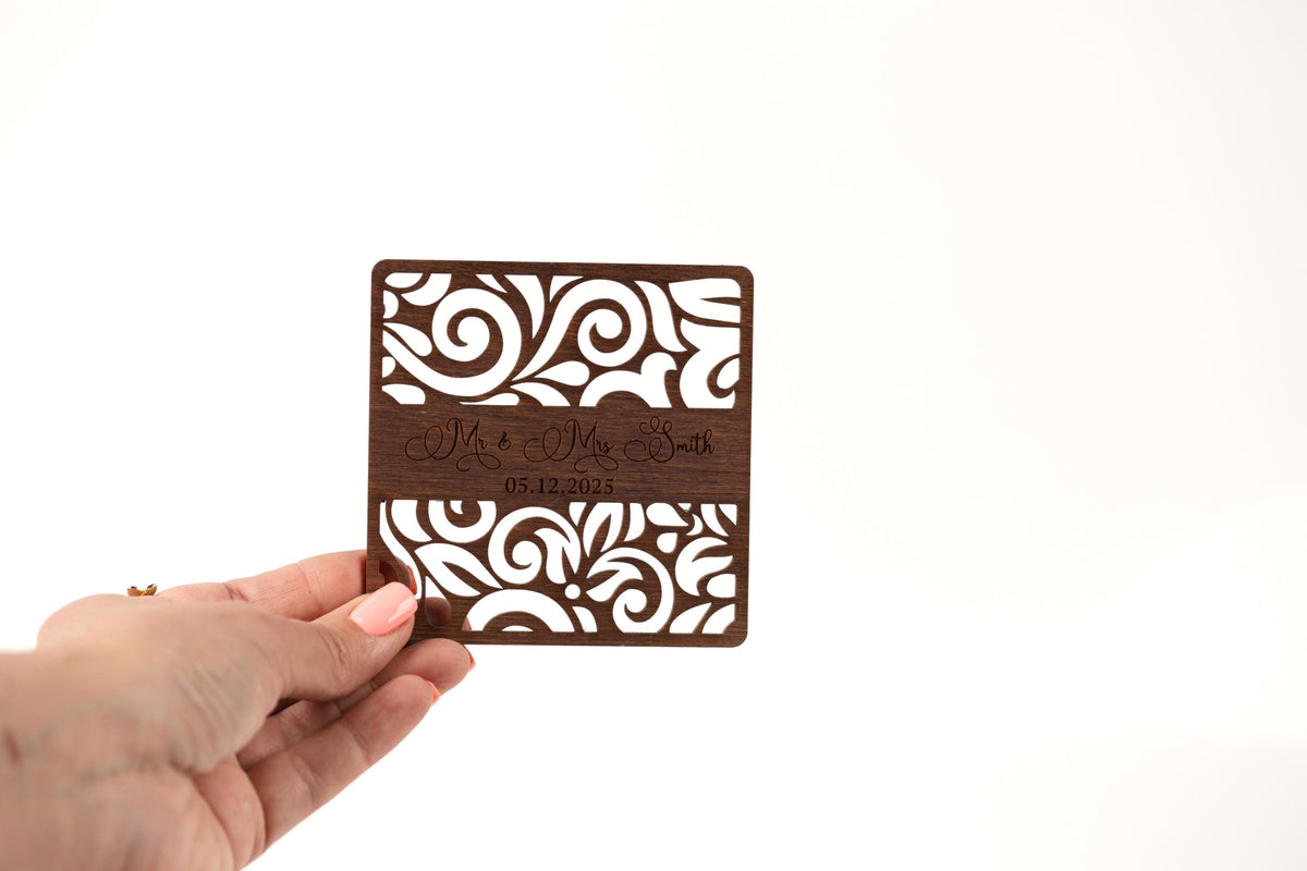 A hand holding a wooden coaster with a decorative pattern on it.