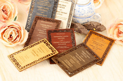 a collection of wooden business cards with intricate designs, placed on a wooden surface alongside some flowers.