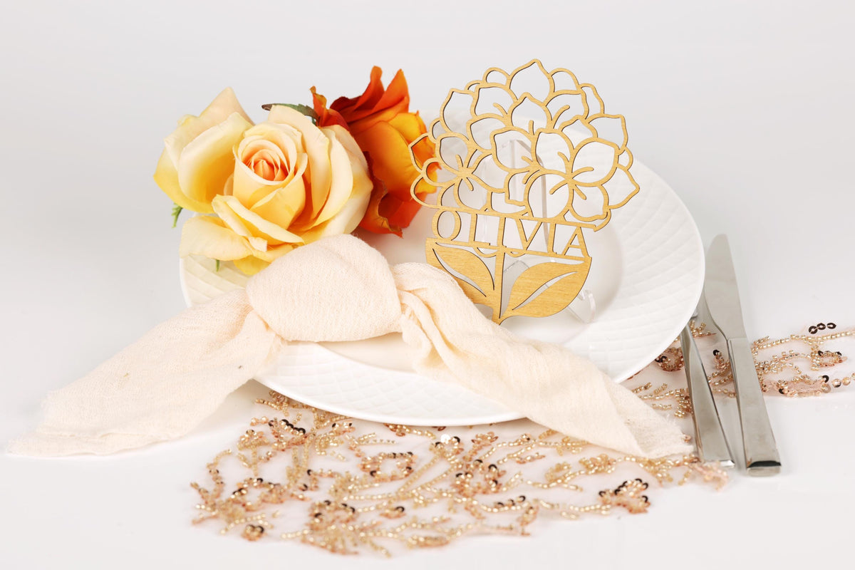 a white plate with a gold floral design, a white ribbon, and a gold flower-shaped napkin holder.