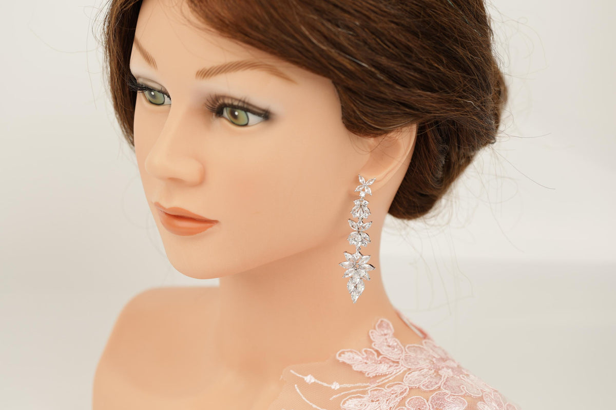 A close-up of a mannequin head wearing a pair of dangling earrings with a floral design.