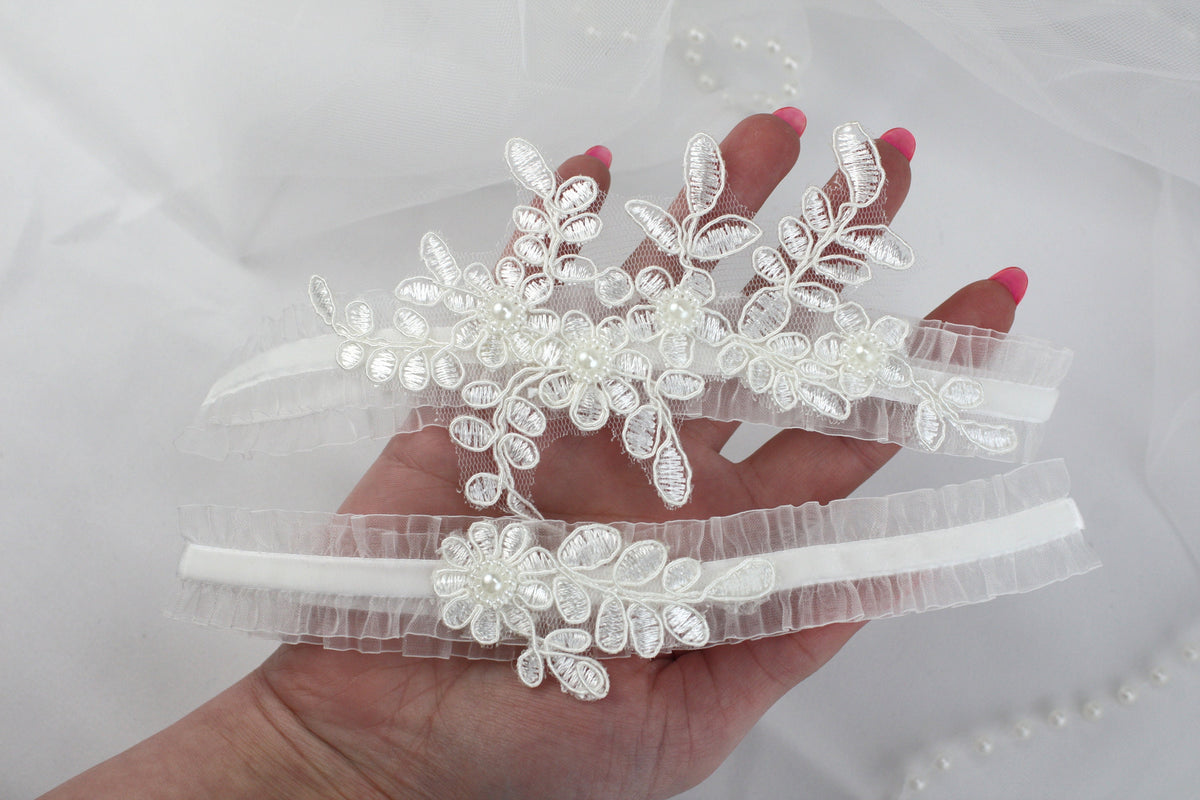 a hand is holding a pair of wedding garters