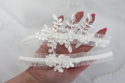 a hand is holding a pair of wedding garters