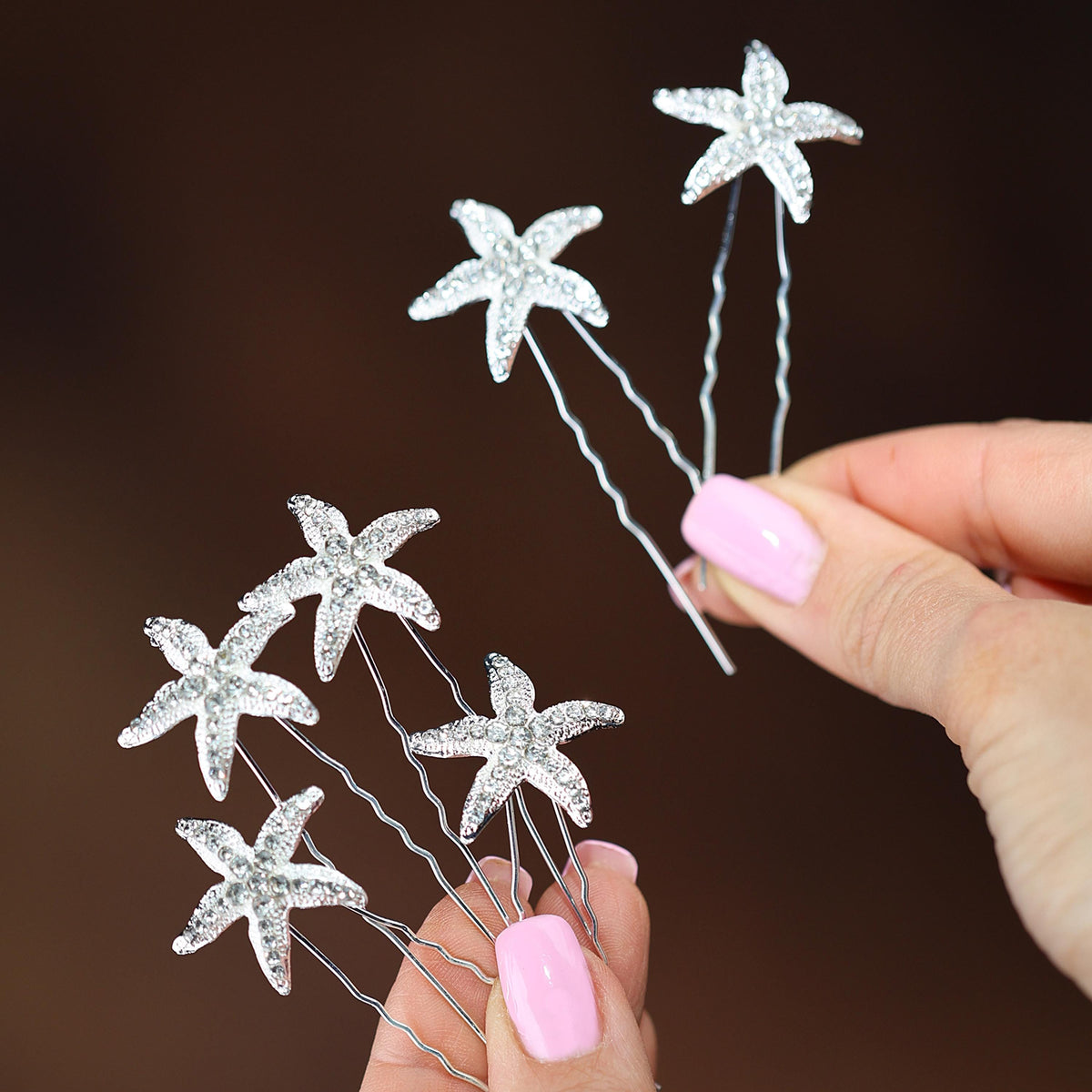 a hand holding a hair pin with starfishs on it