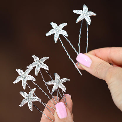 a hand holding a hair pin with starfishs on it