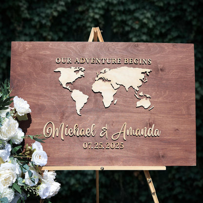 A wooden sign displaying a world map and the names "Michael & Amanda" along with the date "07.25.2025".