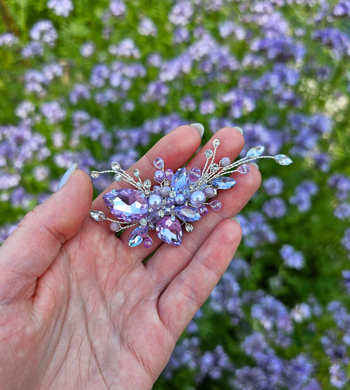 a person is holding a flower brooch in their hand