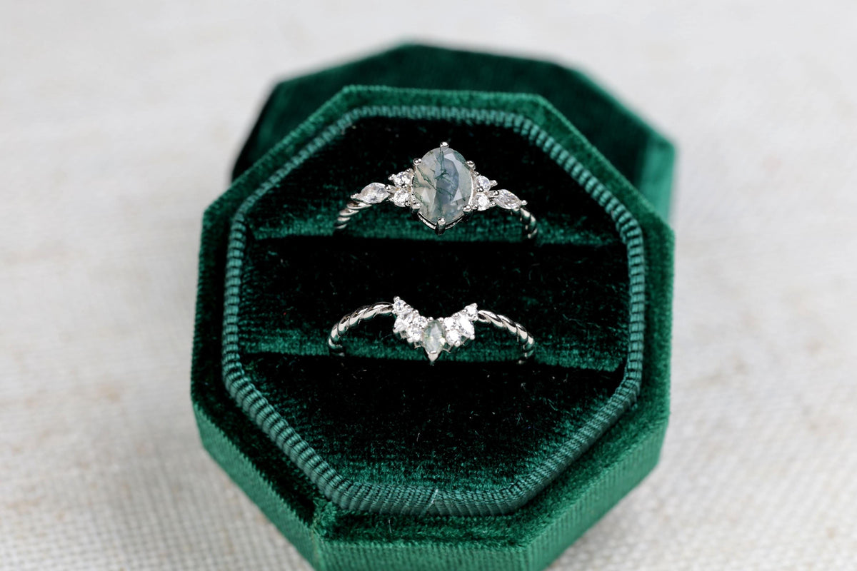 a couple of rings sitting on top of a green velvet box