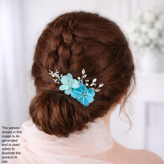 the back view of a woman's head with a bun hairstyle, adorned with a decorative hair accessory featuring blue flowers and silver embellishments.