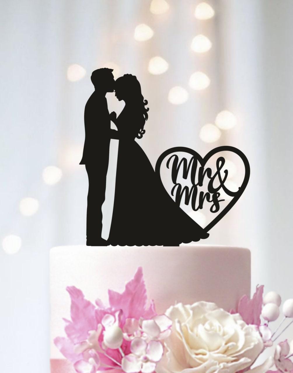 A silhouette of a bride and groom kissing on a wedding cake, with a heart-shaped cutout that says "Mr & Mrs" in the background.