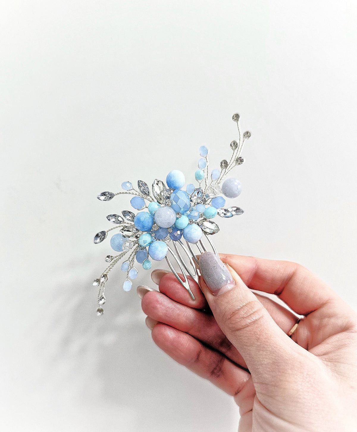 a hand holding a blue and silver hair comb